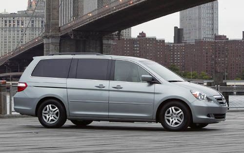 a silver minivan parked in front of a bridge