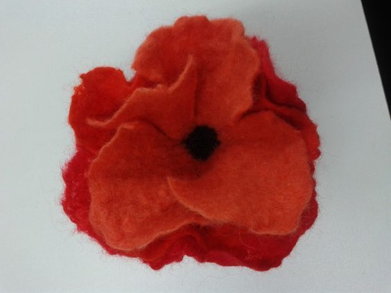 an orange felt flower sitting on top of a white surface