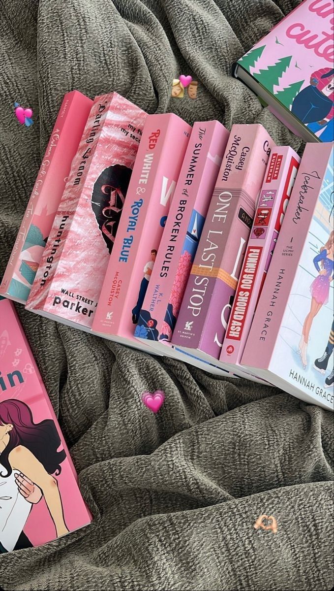 several children's books are laying on a bed with pink covers and confetti