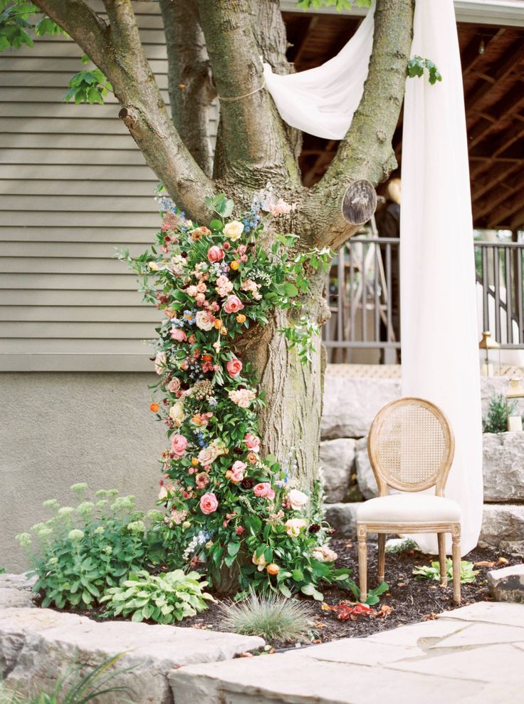 a chair sitting under a tree next to a white curtain