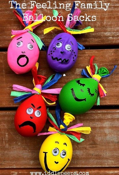 four painted eggs with faces on them sitting on top of a wooden table next to each other