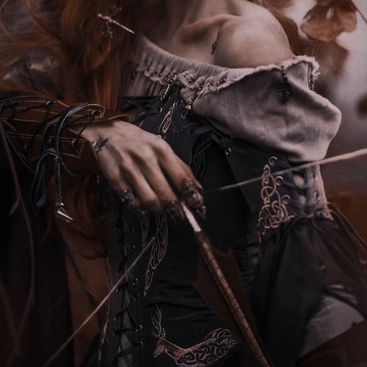 a woman with red hair holding a bow and arrow