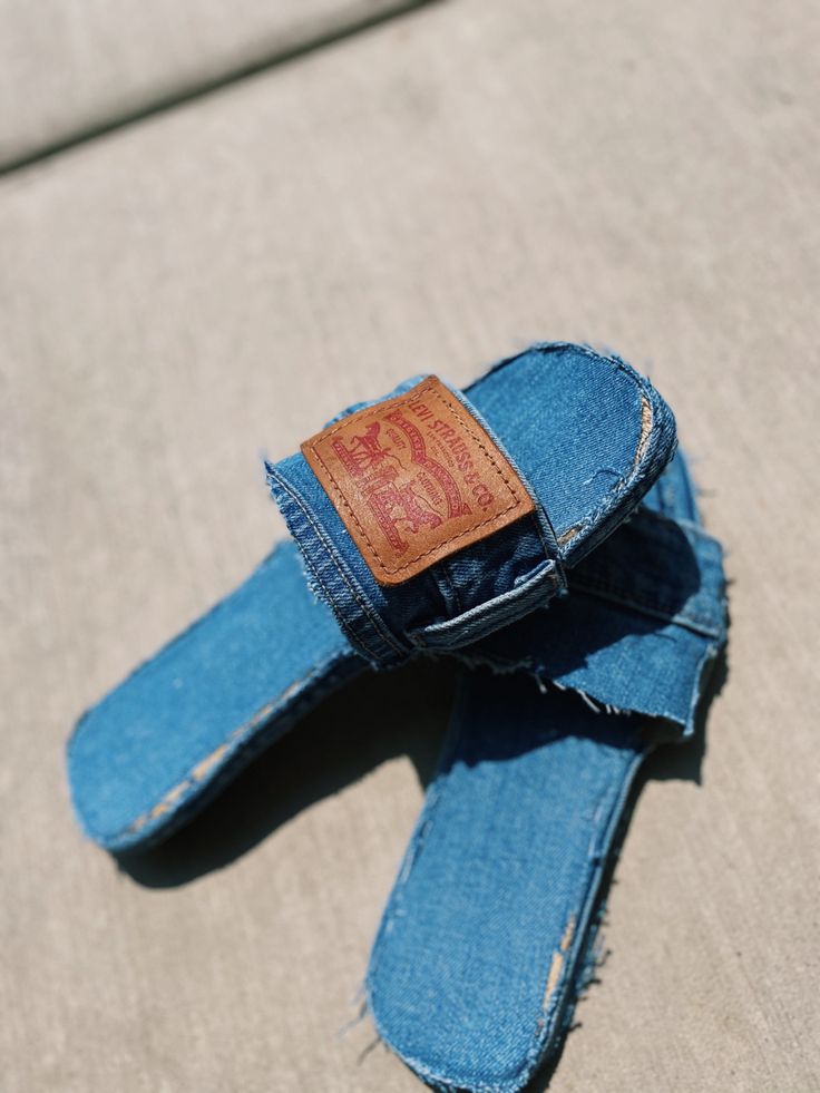 a pair of blue jeans with a leather tag on the back of them sitting on top of a couch