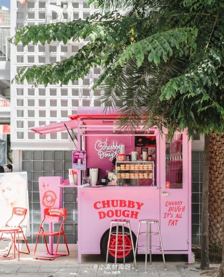 a pink food truck parked next to a tree