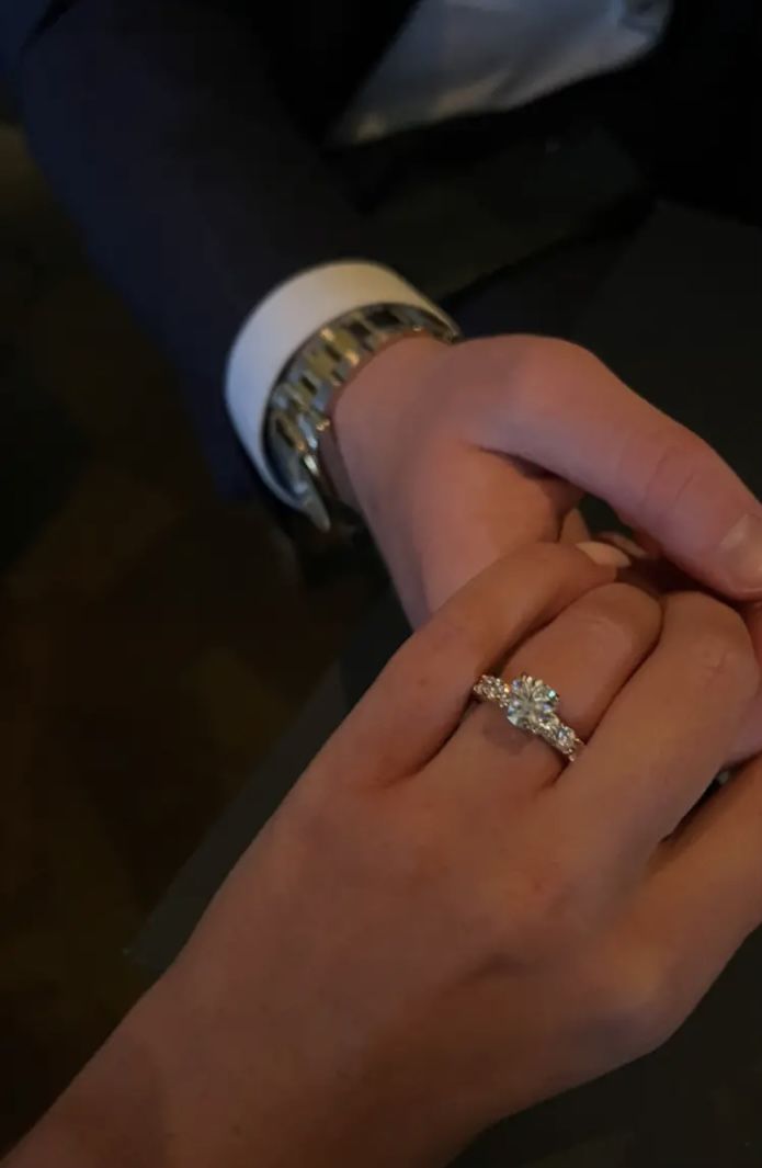 a man and woman holding hands while wearing wedding bands on their fingers, with the bride's engagement ring in her other hand