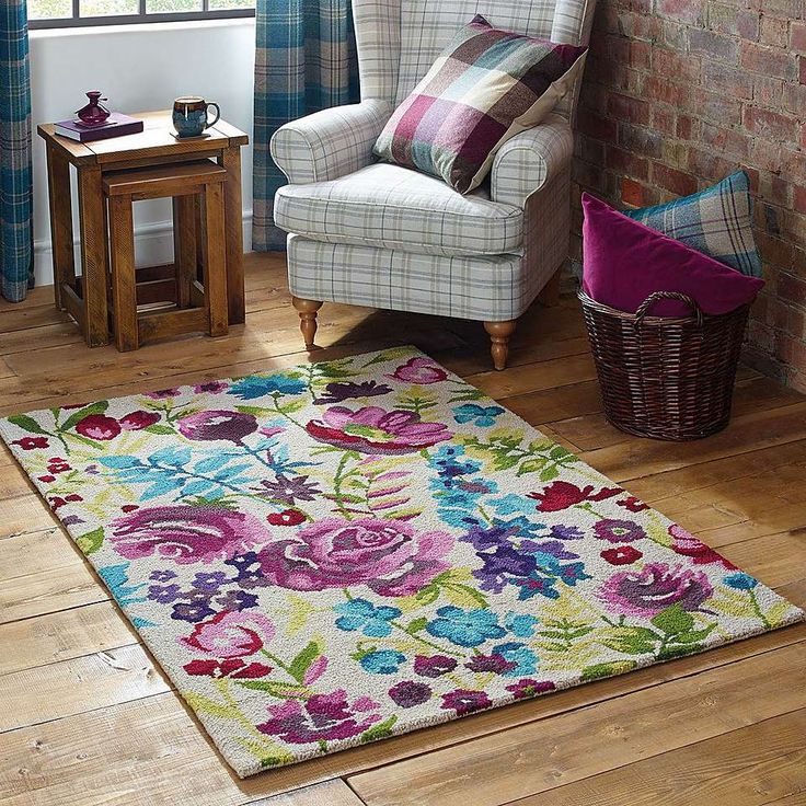 a living room with a chair and rug in front of a brick wall that has flowers on it