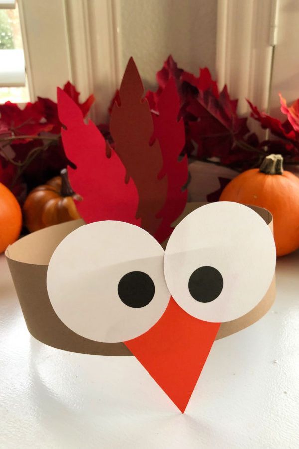 a paper cup with a turkey face on it and some leaves in the back ground