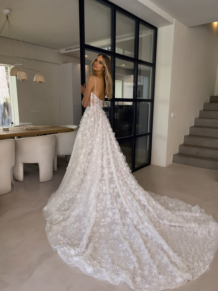 a woman standing in front of a doorway wearing a wedding dress with flowers on it