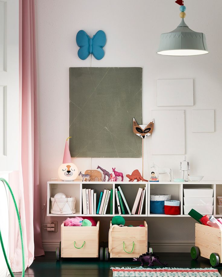 a room filled with lots of toys and books on top of wooden boxes in front of a chalkboard