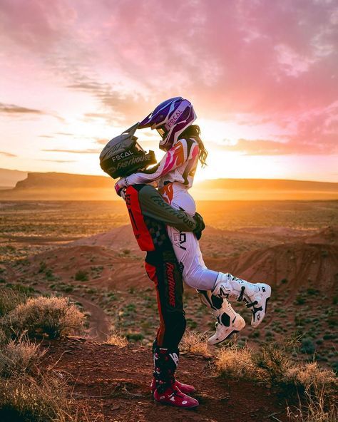 two people standing on top of a dirt field next to each other in the desert