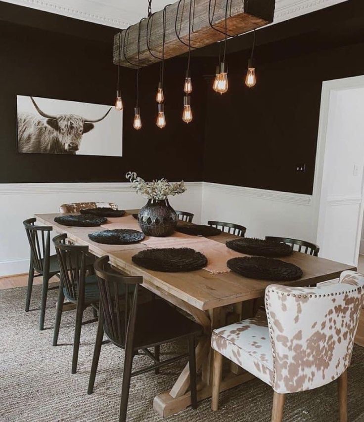 a dining room table with chairs and lights hanging from it's ceiling over it