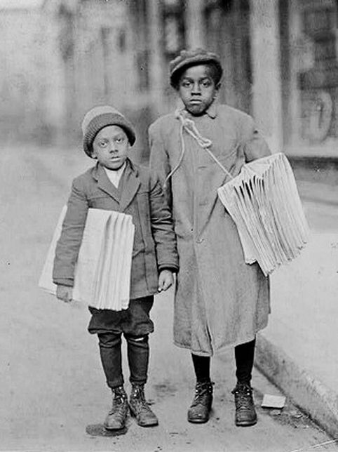 an old black and white photo of two children standing next to each other on the street