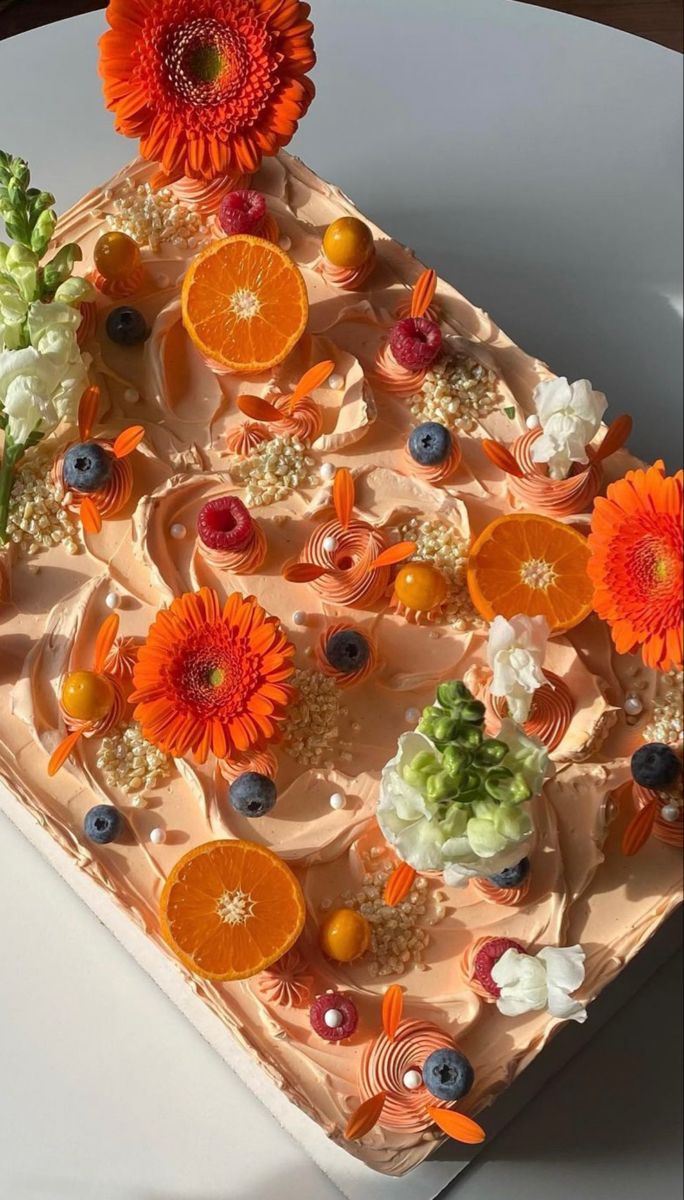 a cake with oranges, blueberries and flowers on it