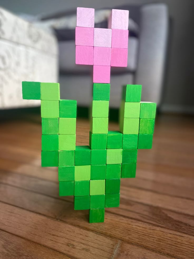 a green and pink piece of paper sitting on top of a wooden floor next to a couch