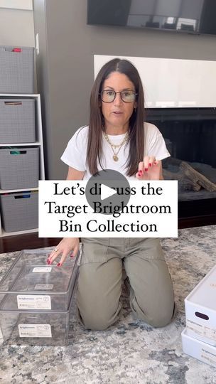 a woman sitting on the floor holding up a sign that says let's do us the target bathroom bin collection