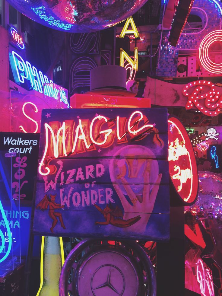 a neon sign that says magic and wizard way wonder in front of other neon signs