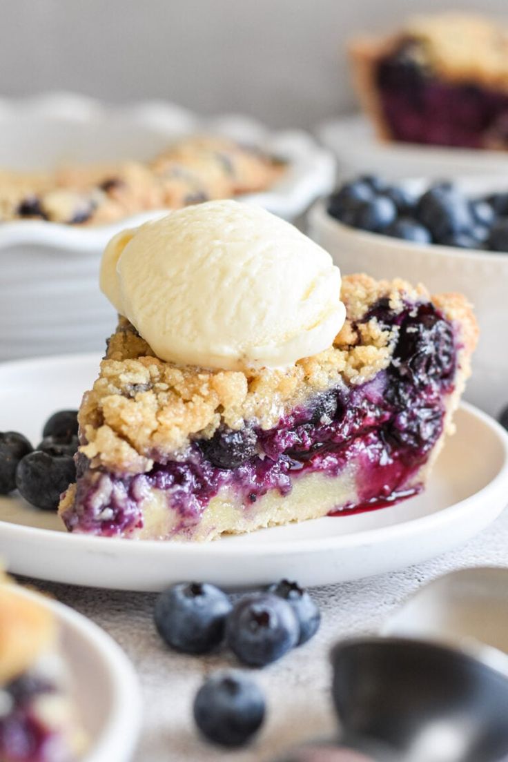 a slice of blueberry crumb pie on a plate with ice cream in the middle