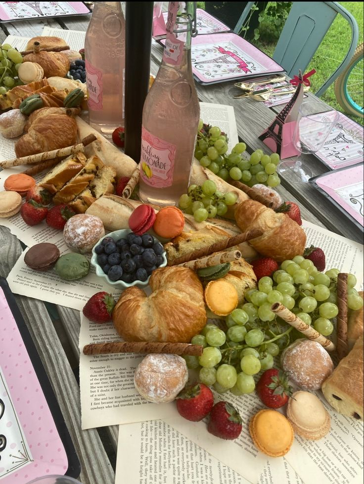 a table topped with lots of different types of pastries and fruit next to wine bottles