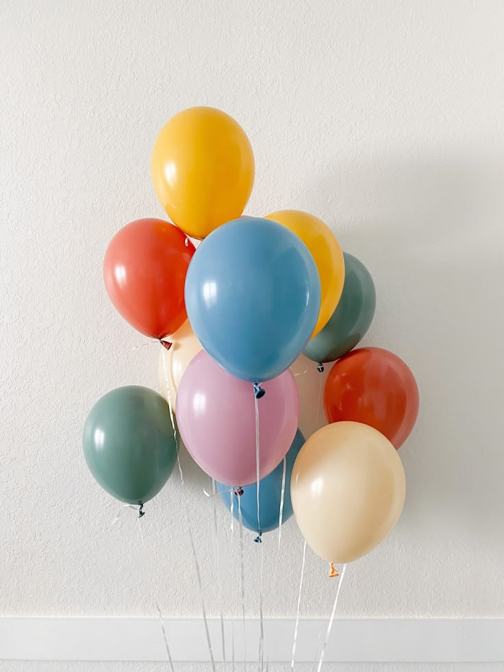 a bunch of balloons floating in the air on top of a table with some sticks sticking out of it