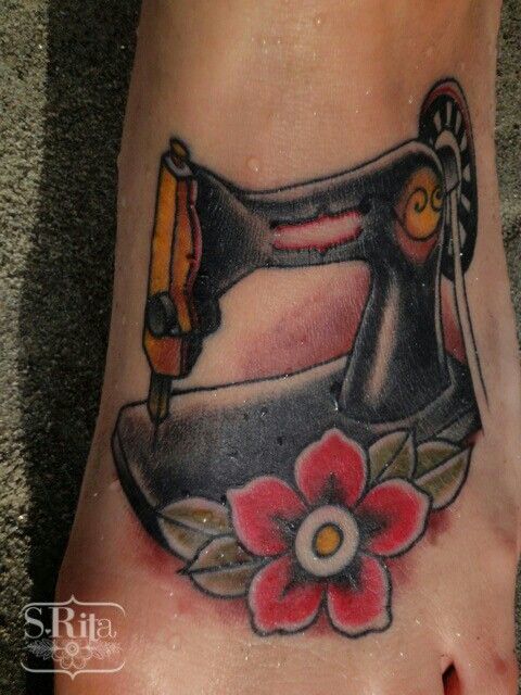 a foot with a sewing machine tattoo on it's left side and a flower in the center