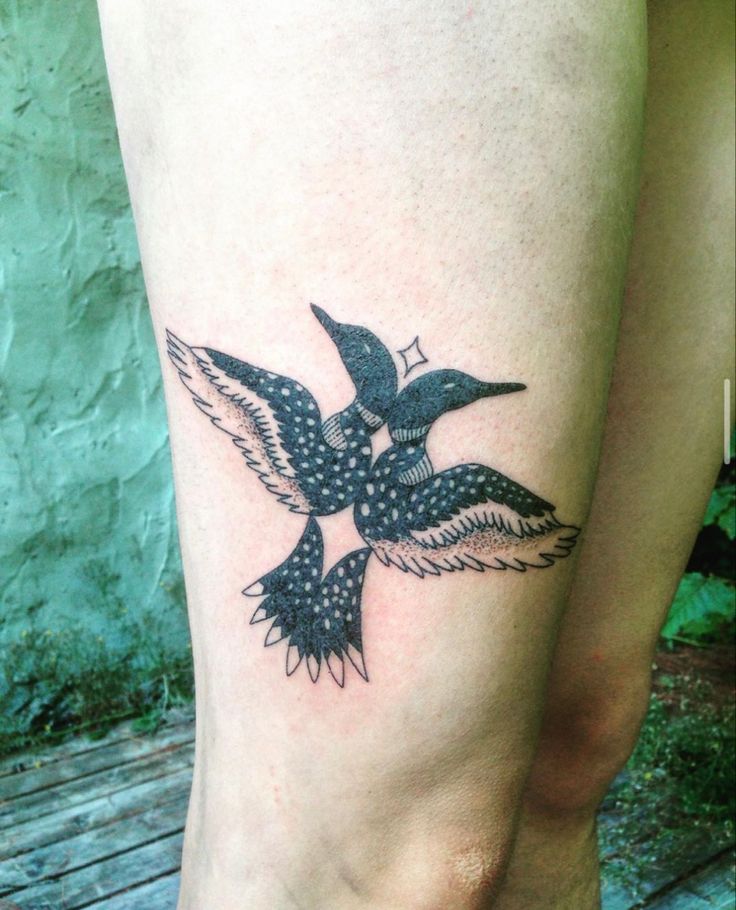 a small tattoo on the leg of a woman with a bird flying over her head