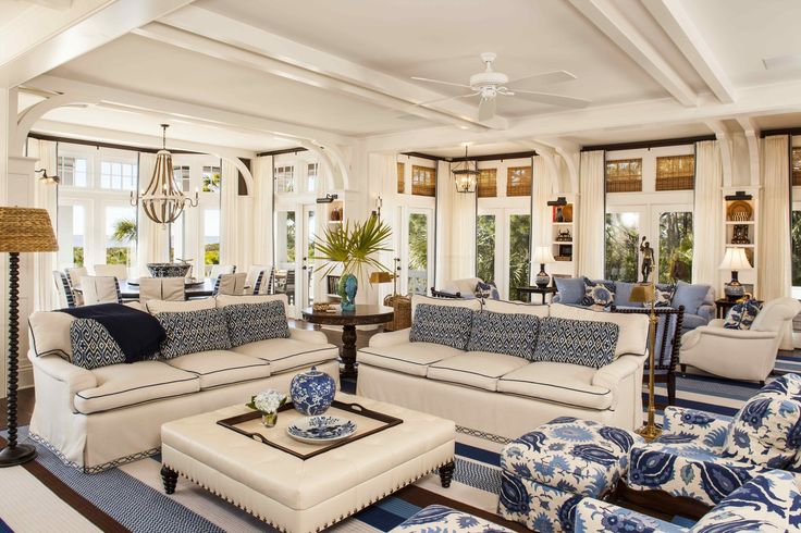 a living room filled with lots of furniture next to tall windows in front of them