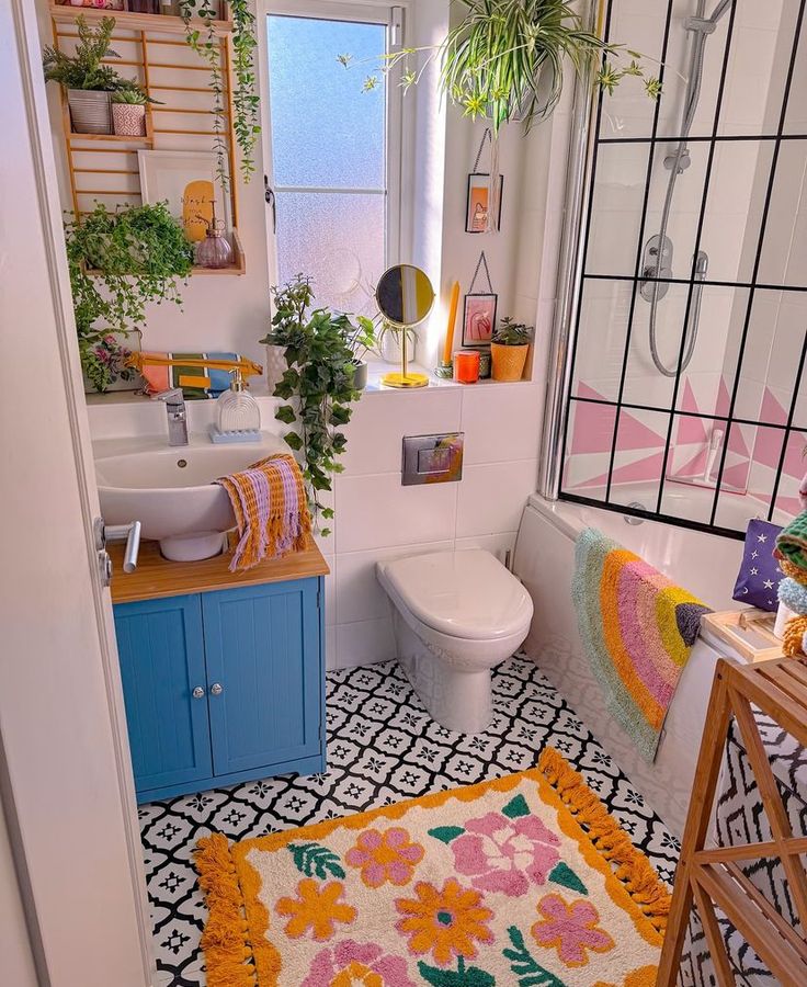 a bathroom with a sink, toilet and bathtub covered in colorful rugs next to a window