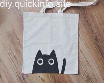 a black and white cat bag sitting on top of a wooden floor