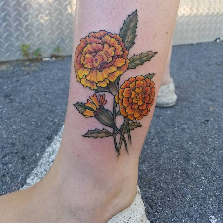 a woman's foot with a flower tattoo on her left leg and yellow flowers in the center