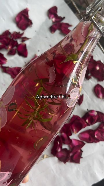 a glass bottle filled with pink flowers on top of a bed of rose petal petals