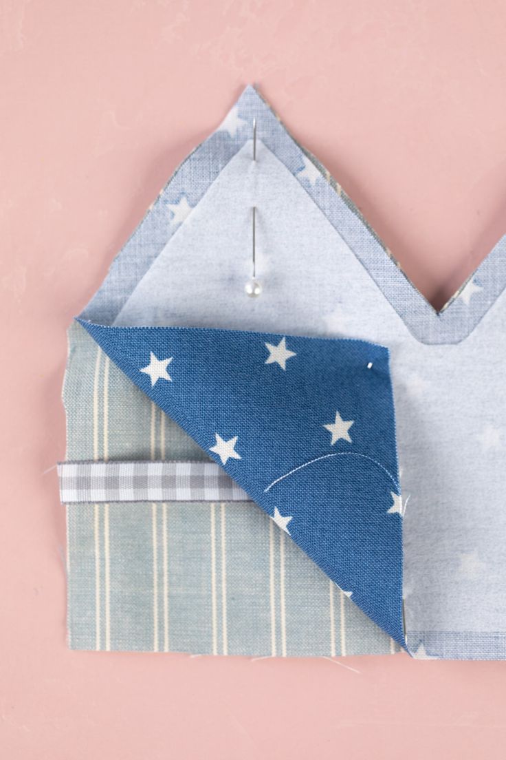 an origami style folded piece of fabric with stars and stripes on it, against a pink background