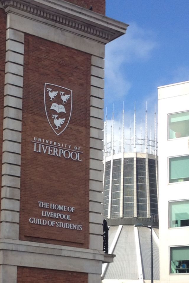 a tall brick building with a clock on it's face in front of the university of liverpool