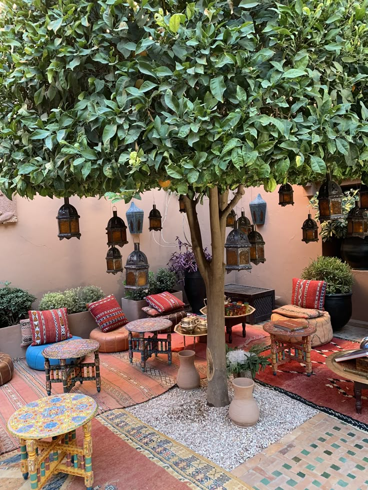 an outdoor seating area with tables and chairs under a tree