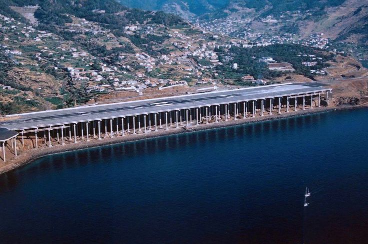 an aerial view of a bridge over a body of water with mountains in the background