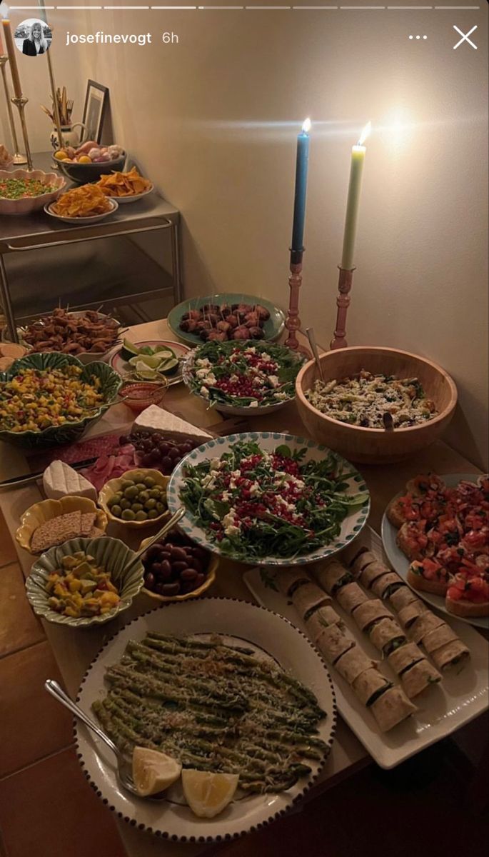 a table filled with lots of food on top of plates next to a lit candle