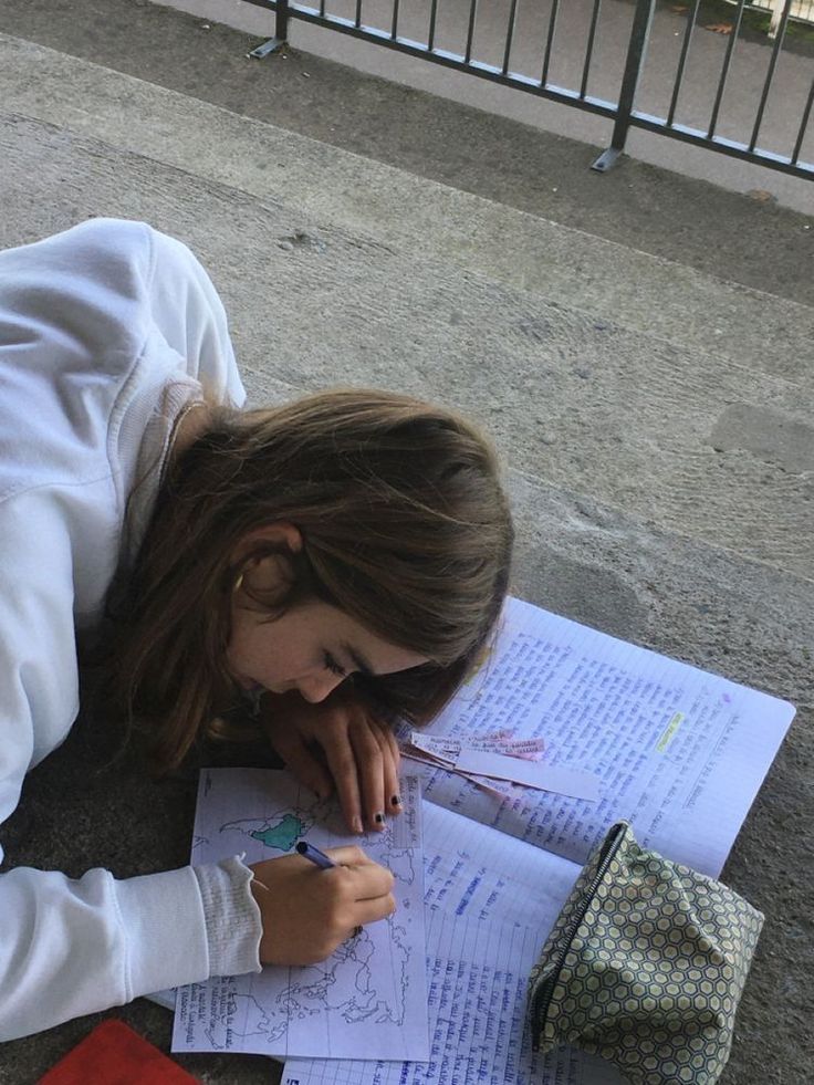 a woman laying on the ground with her head down and writing in front of some papers