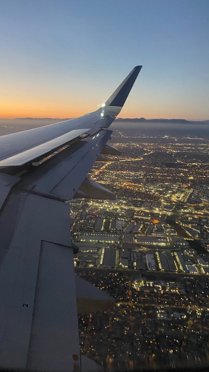 the wing of an airplane flying over a city at night