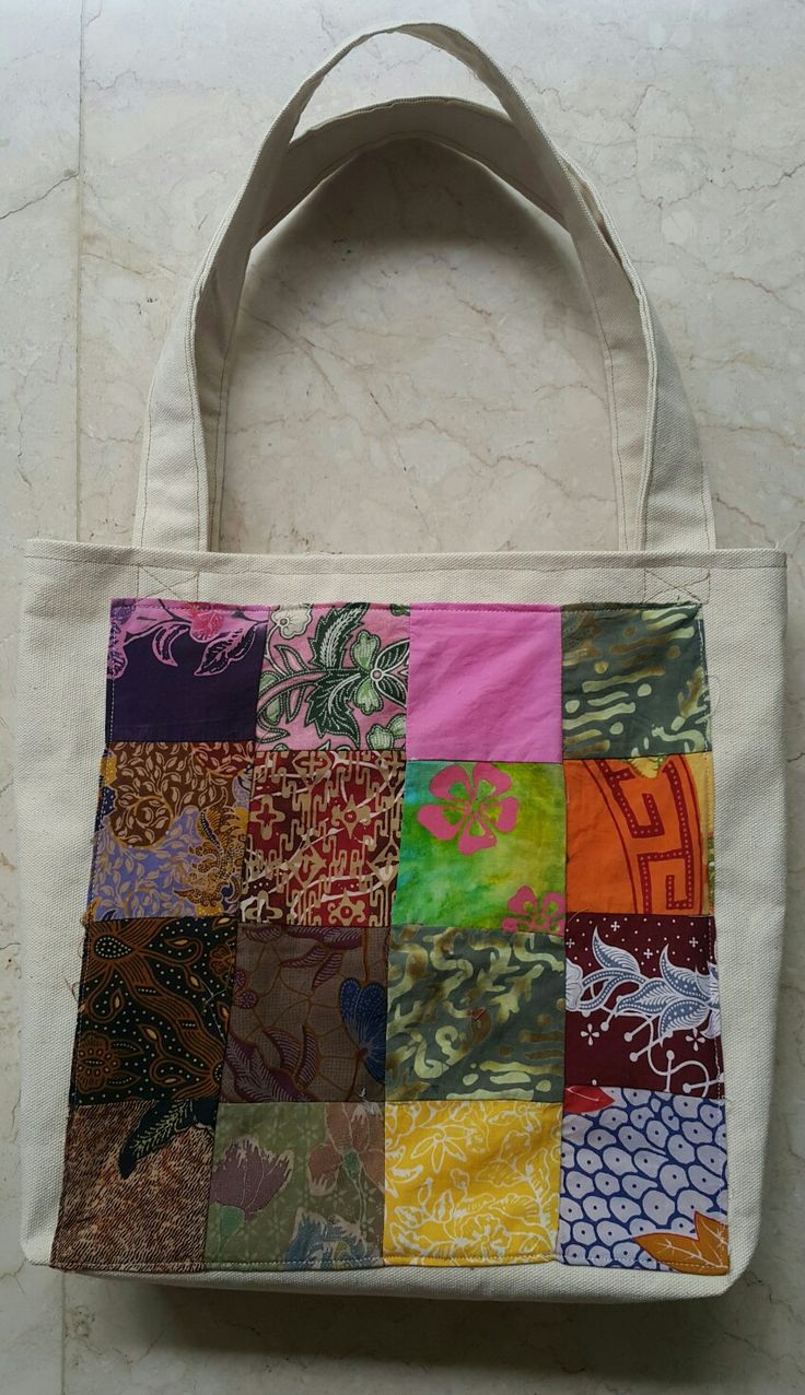 a multicolored patchwork tote bag sitting on top of a white wall