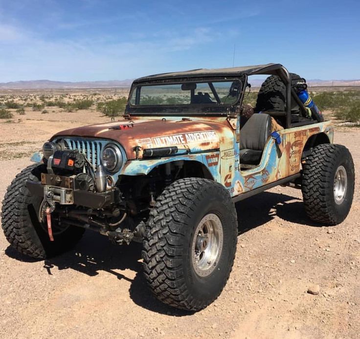 an old rusted jeep is parked in the desert