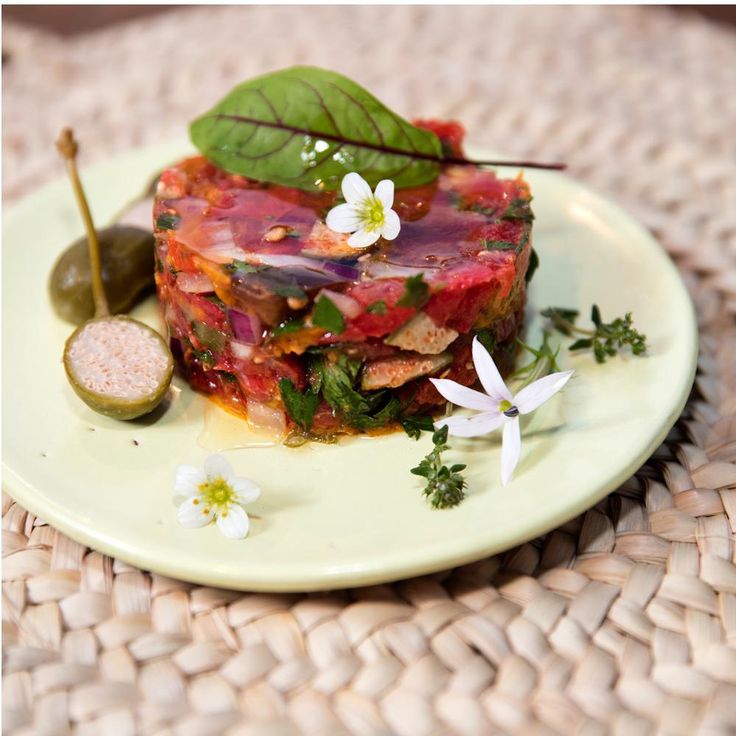 a piece of food is sitting on a plate with some flowers and leaves around it