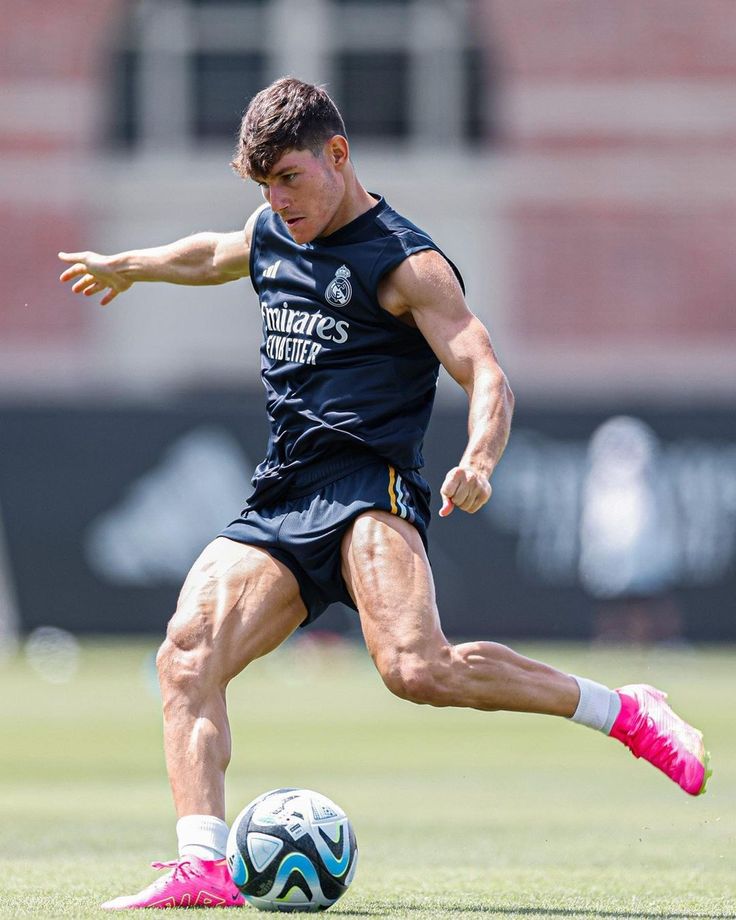 a man kicking a soccer ball on top of a field