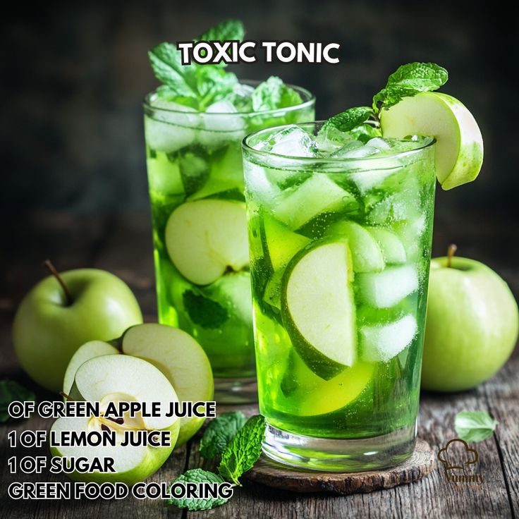 two glasses filled with green apple juice next to sliced apples and mint on a wooden table