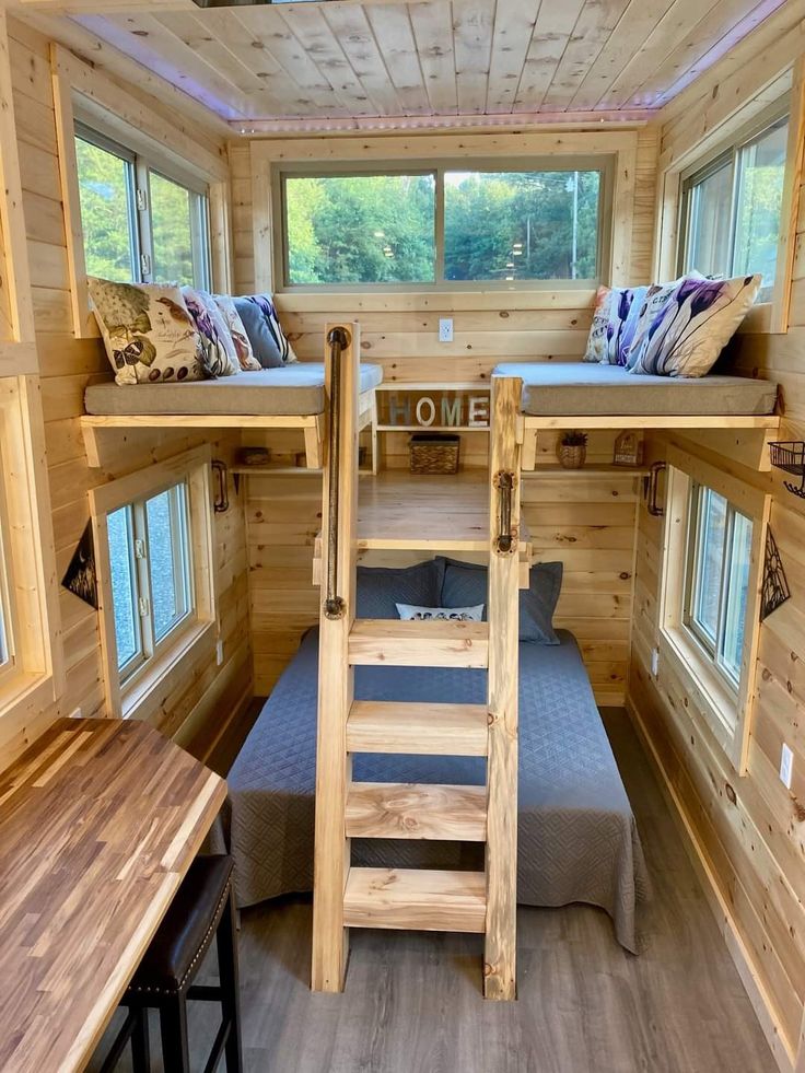 the interior of a tiny cabin with bunk beds and stairs leading up to two windows