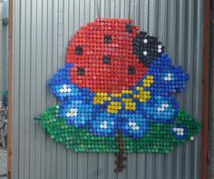 there is a very large piece of art made out of plastic bottle caps and cans