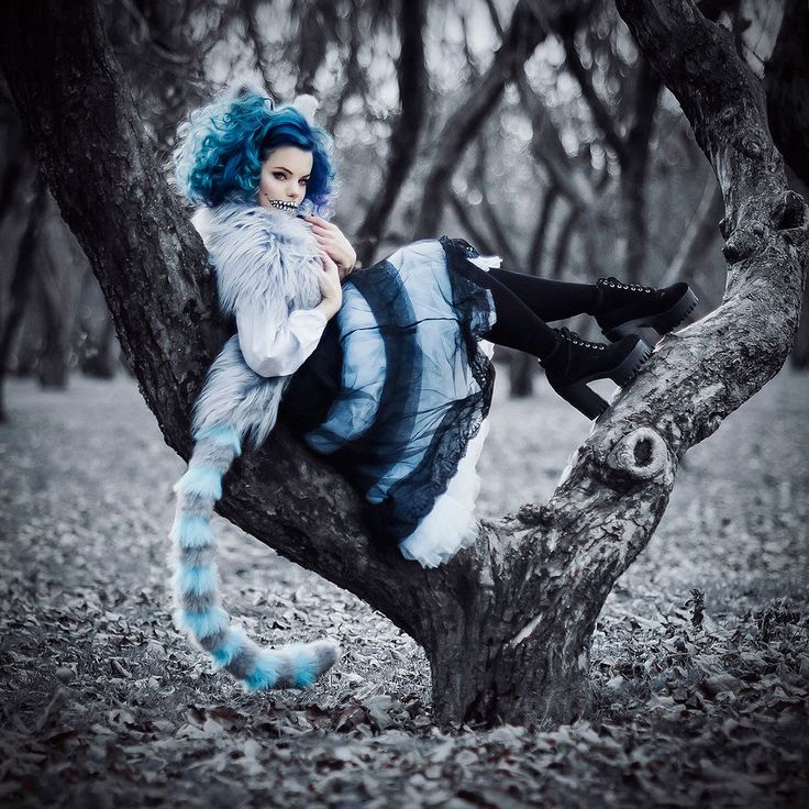 a woman with blue hair is sitting on a tree