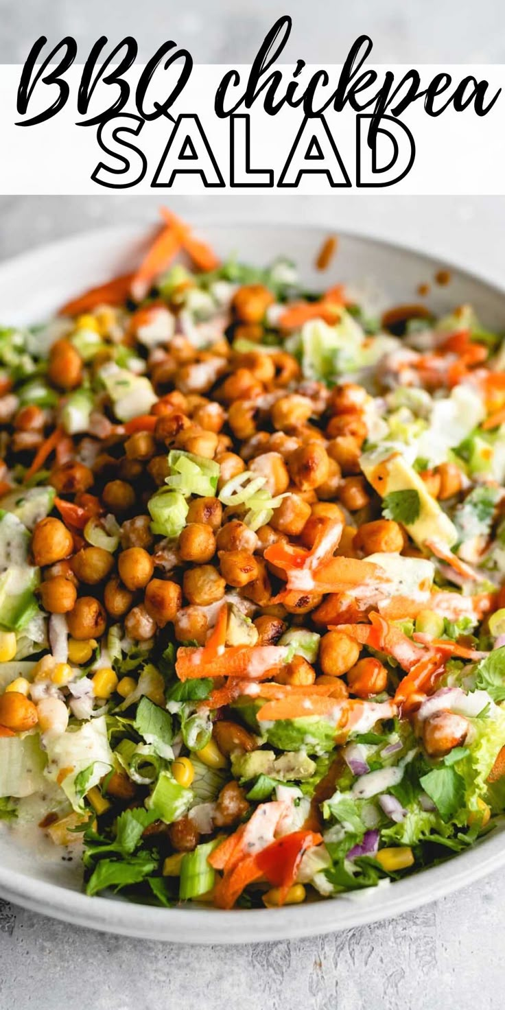 a salad with lettuce, carrots and chickpeas is shown in a white bowl