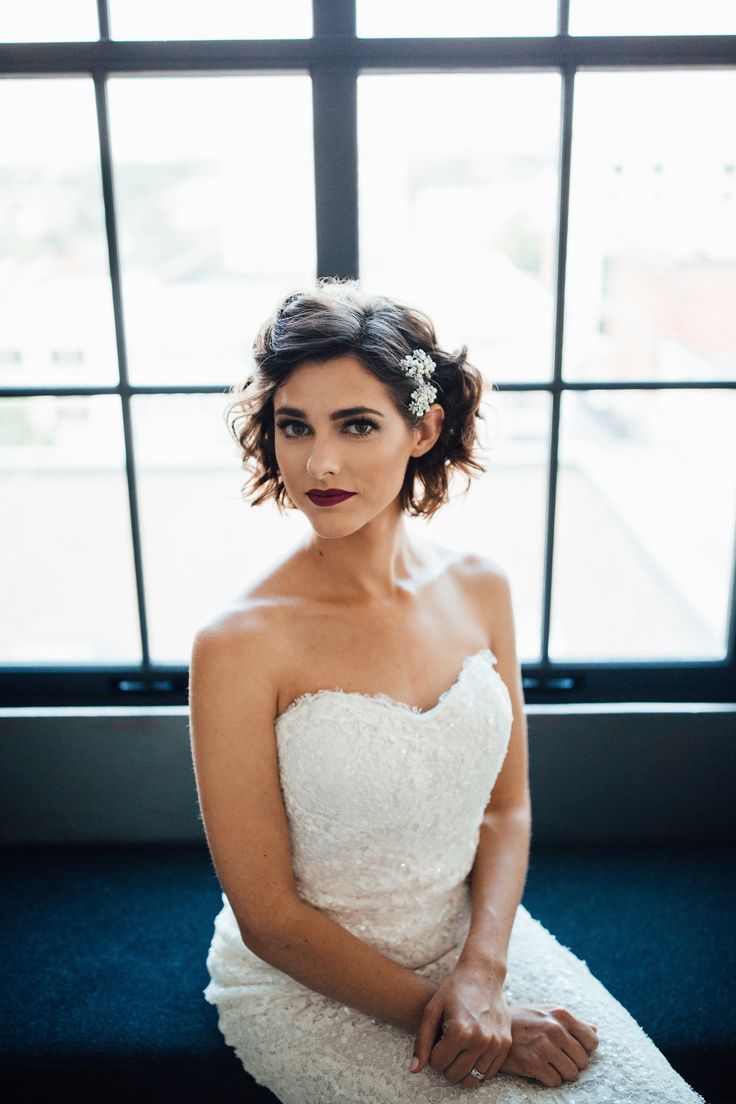 a woman sitting in front of a window wearing a wedding dress