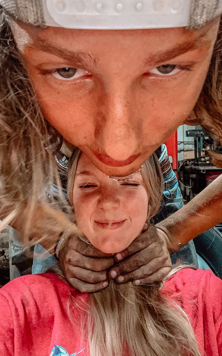 a woman with long hair is holding her face in front of the camera while wearing a hat