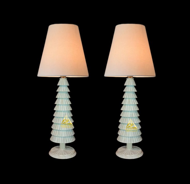 two glass lamps sitting next to each other on a black surface with a white lamp shade