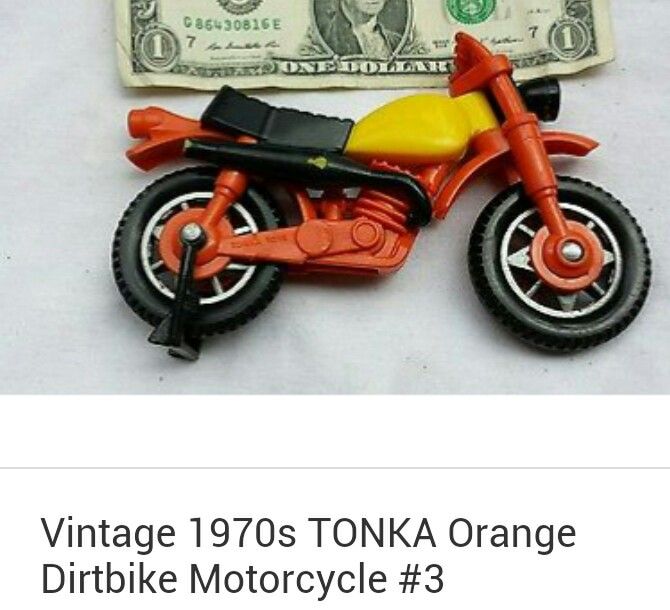 an orange toy motorcycle next to a dollar bill on a white background with the words vintage 1970 tonka orange dirt bike motorcycle 3